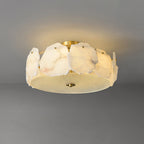 Clérachic ceiling light at a shallow angle, brass studs pinning each alabaster slab to the low drum frame.