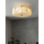 Clérachic flush mount on a plain grey ceiling, a curtain and a leafy plant just below in a quiet corner.