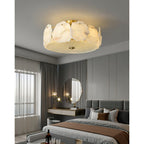 Clérachic flush mount lighting a bedroom with a brass vanity, round mirror and full-length curtains.