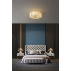 The Clérachic ceiling light over a deep-buttoned bed set into a blue alcove, alabaster glowing softly.