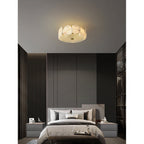 Clérachic flush mount seen from across a dark bedroom, a small warm disc against the pale ceiling.