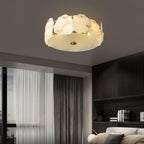 The Clérachic ceiling light in a dim room with heavy curtains, its alabaster ring the brightest point.
