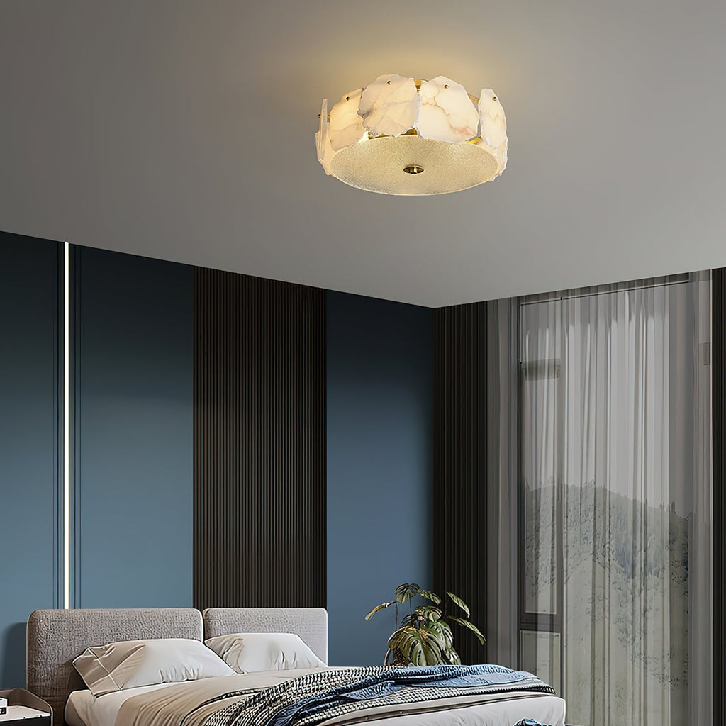 The Clérachic ceiling light in a blue-walled bedroom, glowing gently above the bed beside a tall plant.