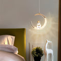 Clérachic moon pendant light glowing beside a mustard headboard, its light casting soft rays on the wall.