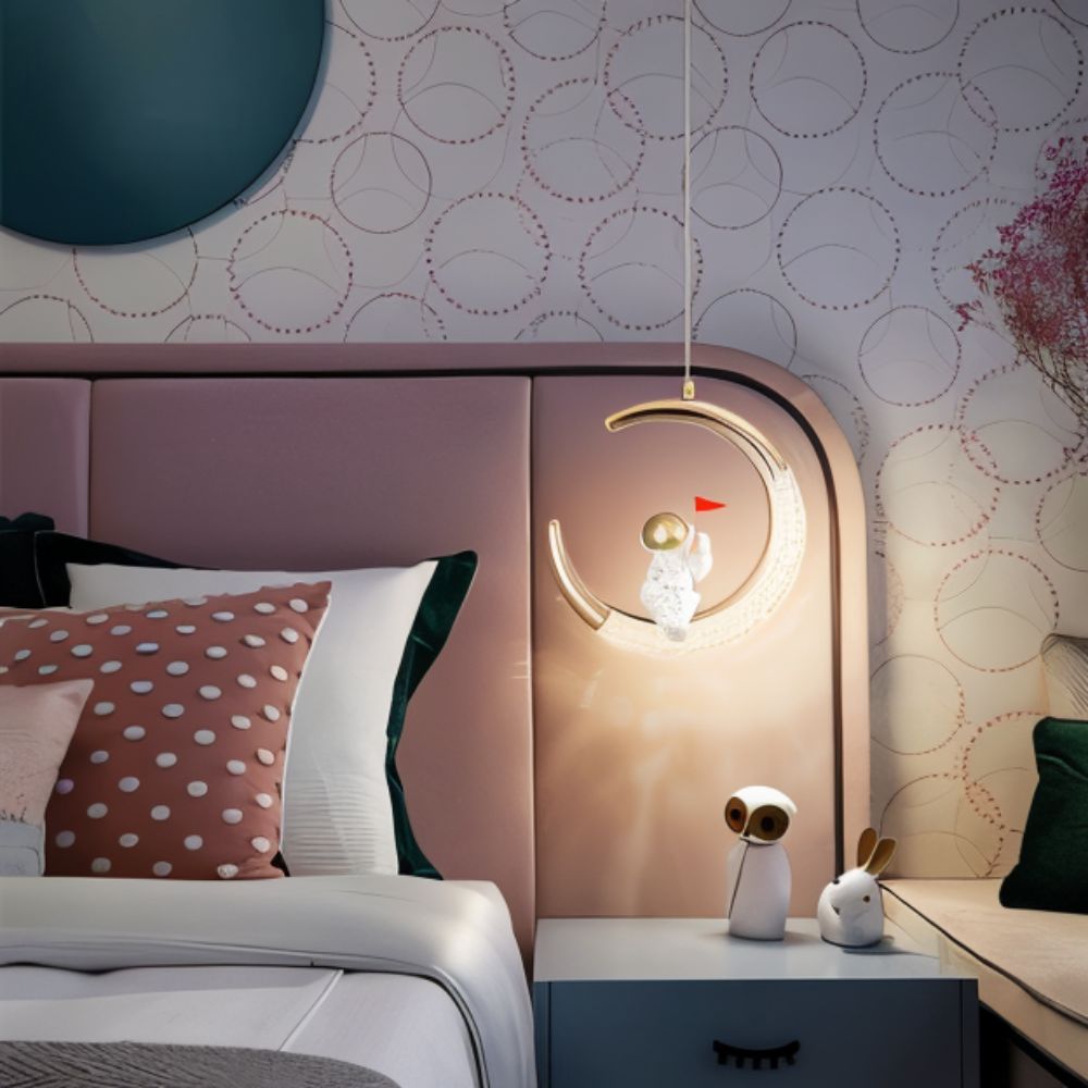 Clérachic moon pendant light glowing beside a pink upholstered headboard in a child's bedroom.