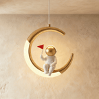 Clérachic moon pendant light in gold, a small astronaut figure seated on the glowing inner edge.