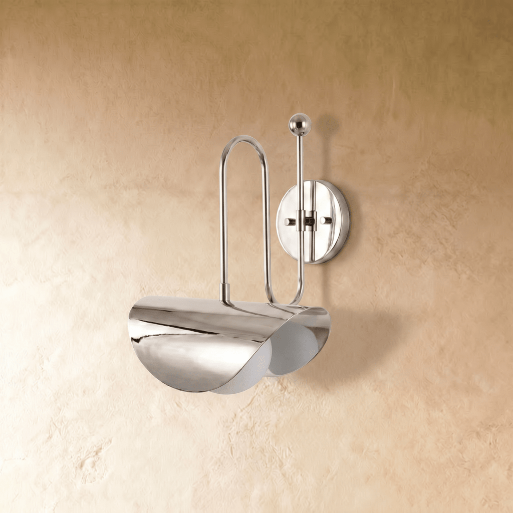 Clérachic curved-arm wall sconce in polished chrome, shown from a slightly closer studio angle on a plaster wall.