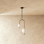 Clérachic pendant light with its two opal globes collared in black top and bottom, each finishing in a short tail below the glass.