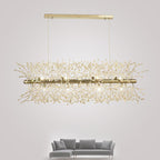 Product shot of a gold-finish rectangular bar pendant beside the edge of a grey sofa, a different Clérachic fixture from this chandelier.