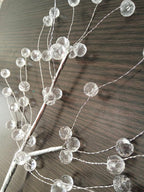 Close view of a single crystal-tipped branch from this Clérachic chandelier against a dark wood backdrop.