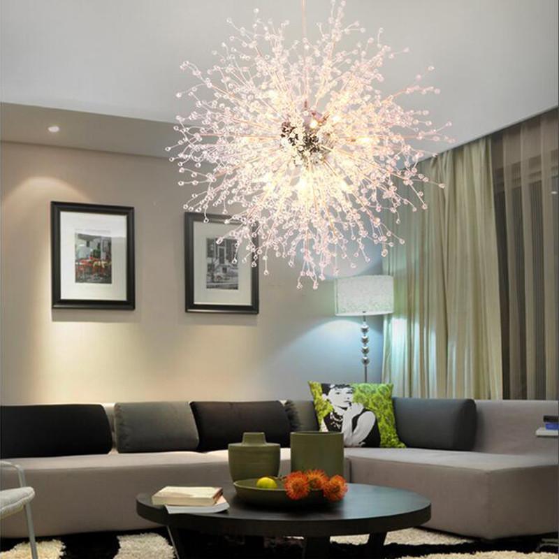 This Clérachic chandelier hangs lit in a neutral living room with a grey sofa and a floor lamp.