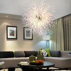 This Clérachic chandelier hangs lit in a neutral living room with a grey sofa and a floor lamp.