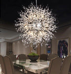 This Clérachic chandelier hangs above a dining table set with upholstered chairs and a marble bowl centrepiece.
