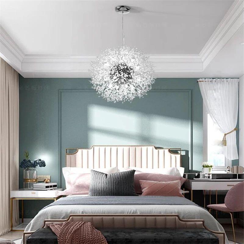 This Clérachic chandelier hangs lit in a teal-walled bedroom with a tufted headboard and a pink cushion.