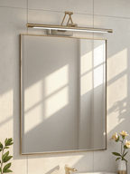 Slim gold frame light highlighting a piece of wall art