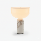 This Clérachic sphere table lamp in grey-veined white marble, lit and photographed against a plain grey background.