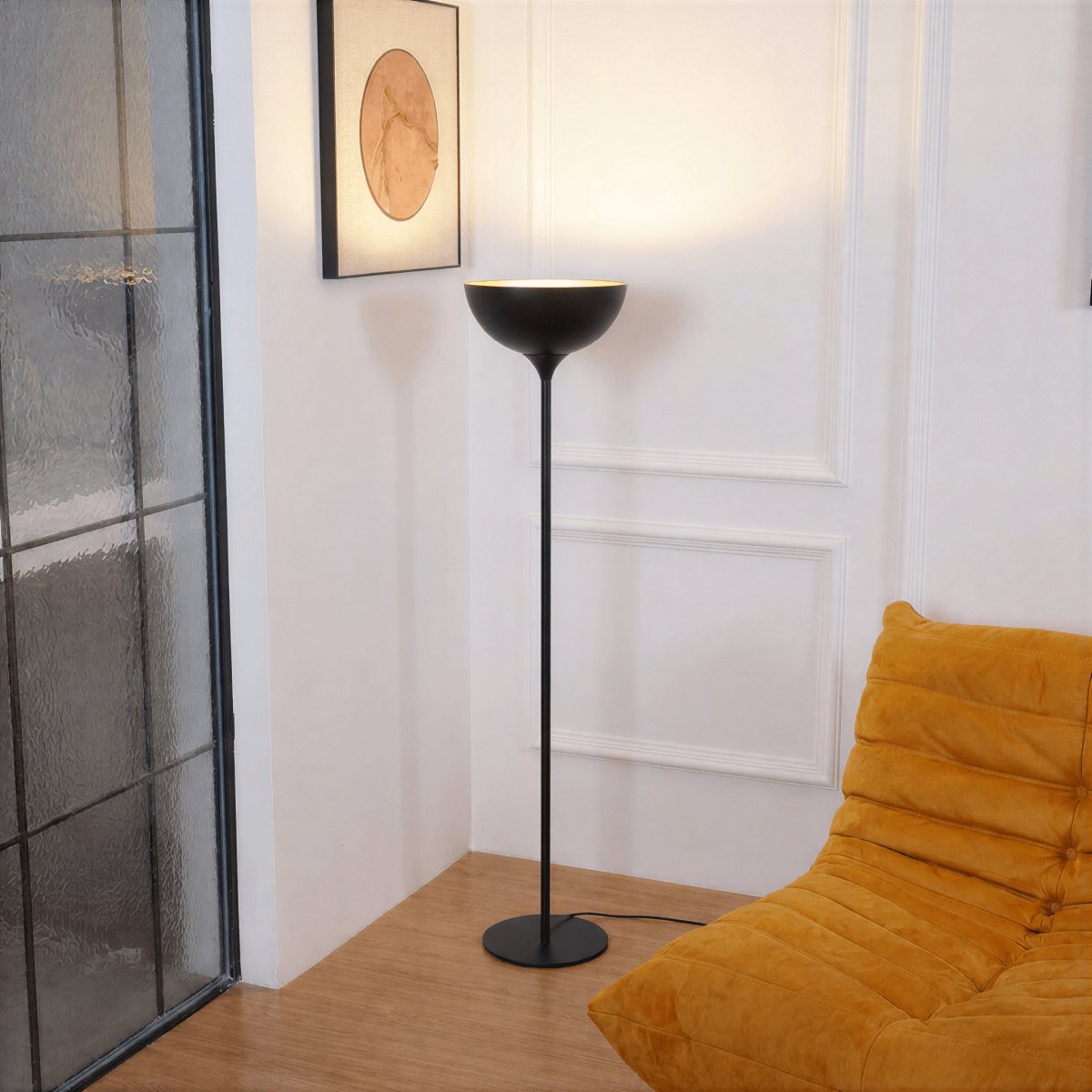 Clérachic matte black floor lamp glowing beside a mustard velvet chair and framed art near a glazed door.