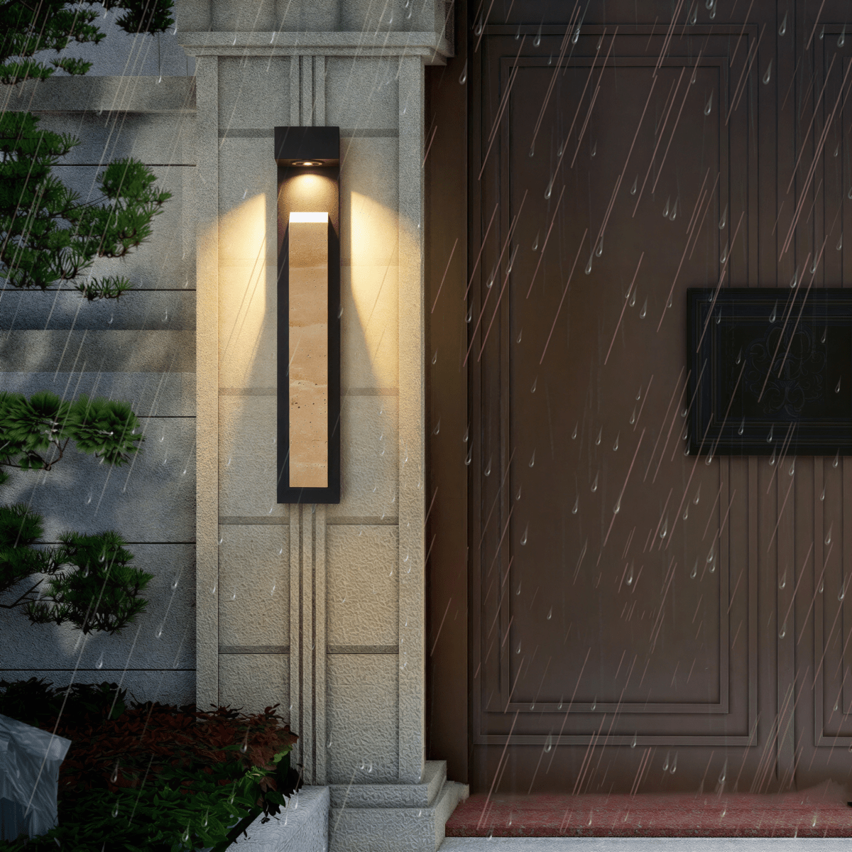 Clérachic wall lamp mounted on a narrow fluted pillar and lit through falling rain, beside a dark panelled door.