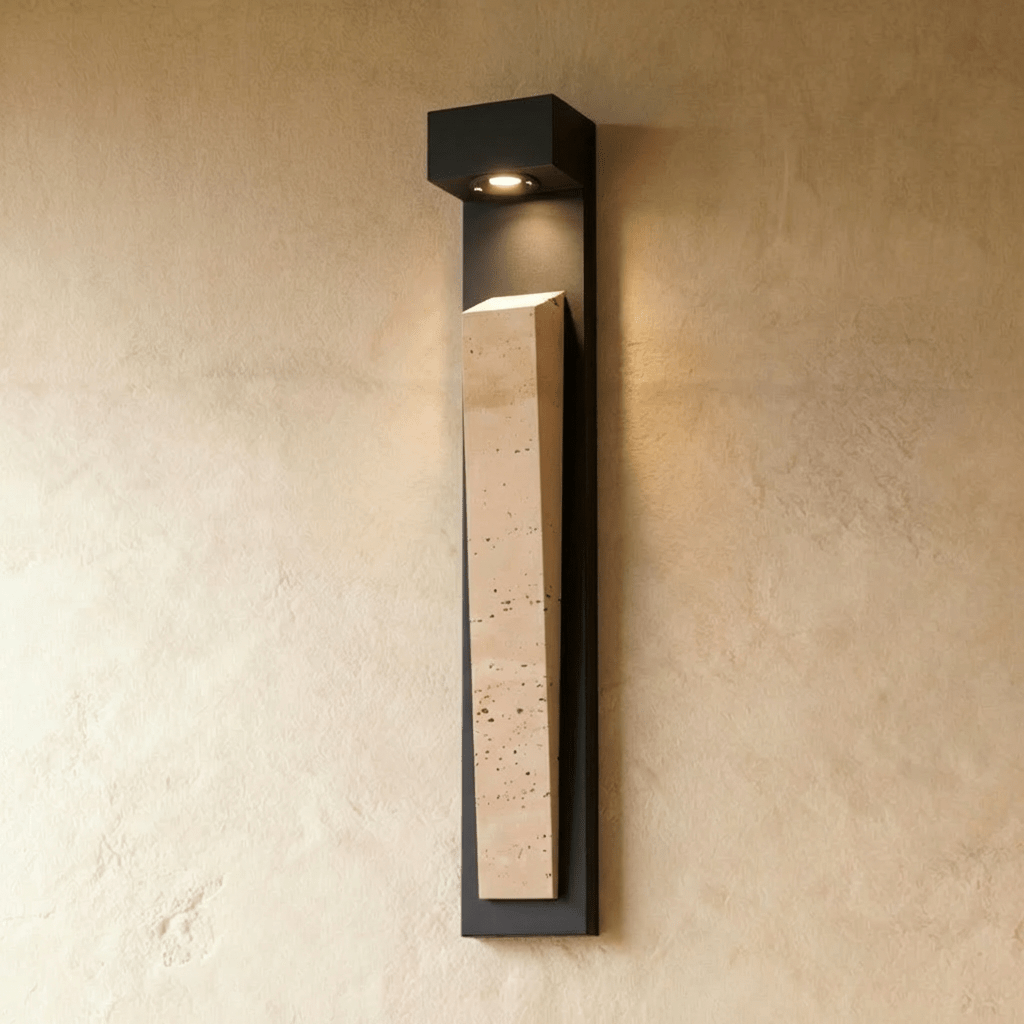 Clérachic travertine wall lamp lit on a warm-toned textured wall, the light in its canopy washing down the stone's face.
