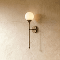Clérachic wall lamp in vintage brass with a round frosted glass globe on a slender tapering stem.