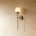 Clérachic wall lamp in vintage brass with a round frosted glass globe on a slender tapering stem.