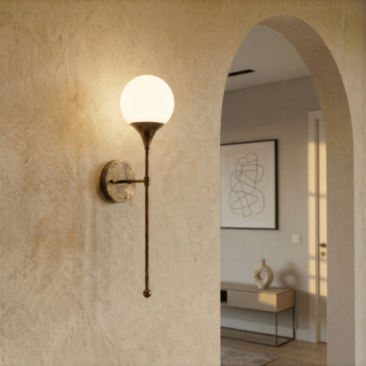 Clérachic wall lamp in brass lighting a plastered archway near a console table and abstract print.