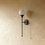 Clérachic wall lamp in matte black, close view of the glass globe and its slim mounting arm.