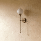 Clérachic wall lamp in vintage brass, close view of the glass globe and slim mounting arm.