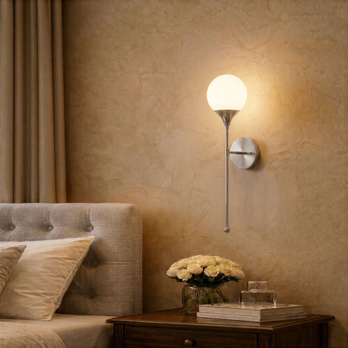 Clérachic wall lamp in chrome lighting a bedroom nightstand set with a vase of white roses.