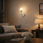 Clérachic wall lamp in chrome glowing above a sofa beside a table lamp and framed seascape.