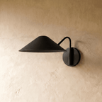 Clérachic cone-shade wall sconce in matte black, shown from a slightly closer studio angle on a plaster wall.