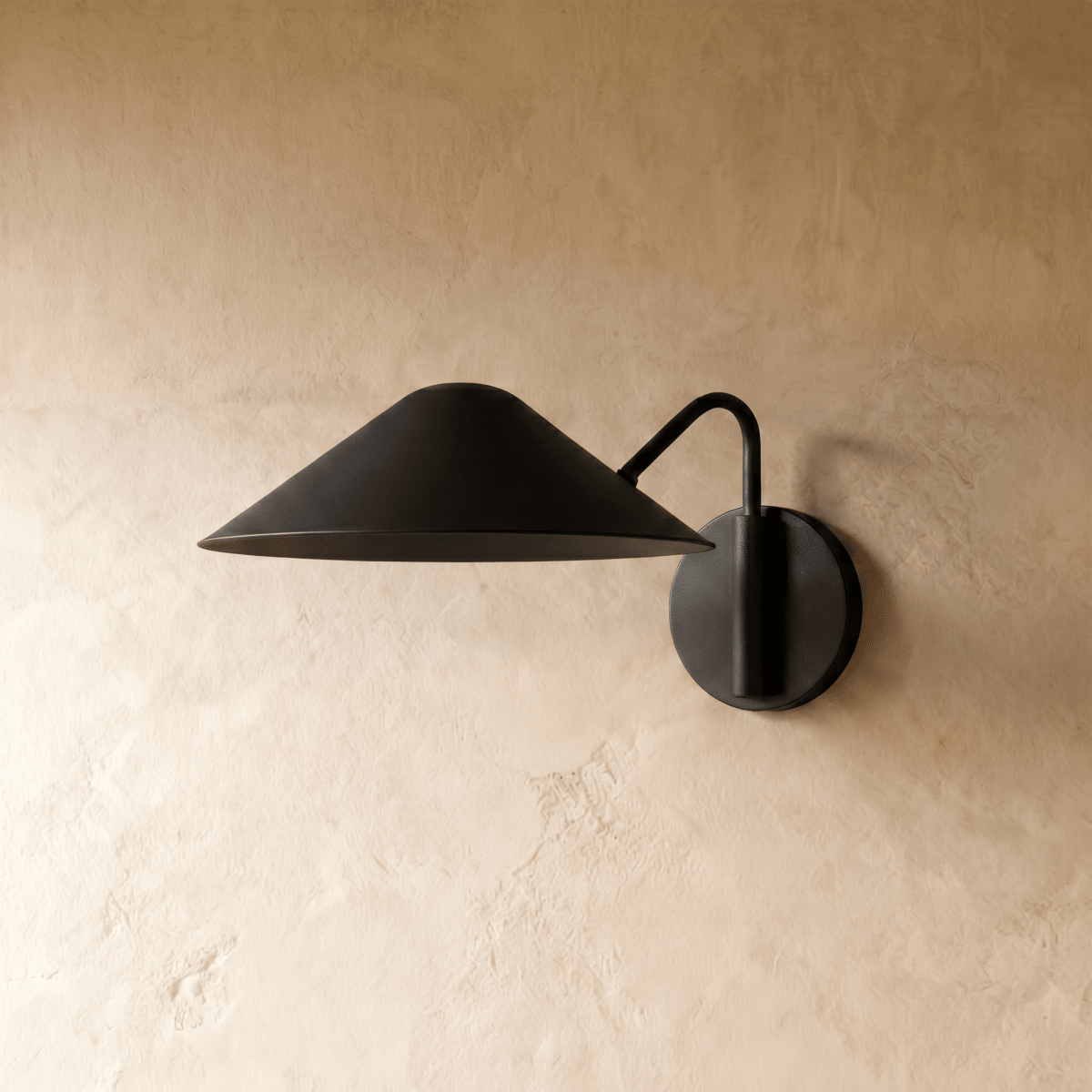 Clérachic cone-shade wall sconce in matte black, shown from a slightly closer studio angle on a plaster wall.