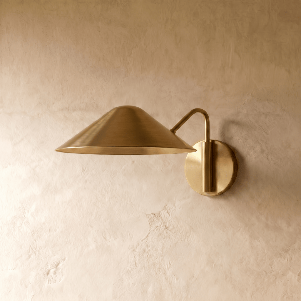 Clérachic cone-shade wall sconce in polished brass, shown from a slightly closer studio angle on a plaster wall.