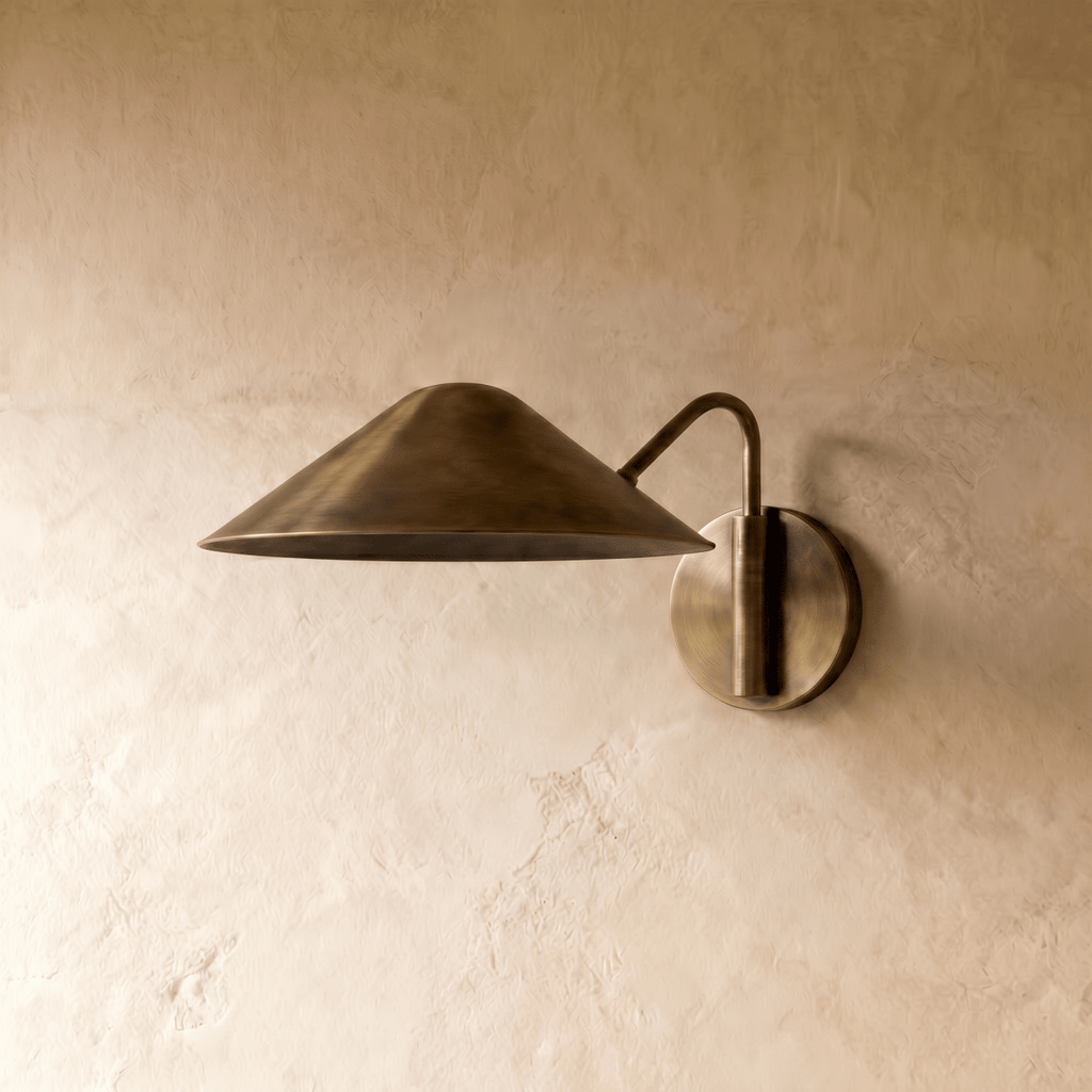 Clérachic cone-shade wall sconce in vintage brass, shown from a slightly closer studio angle on a plaster wall.