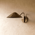 Clérachic cone-shade wall sconce in vintage brass, shown from a slightly closer studio angle on a plaster wall.