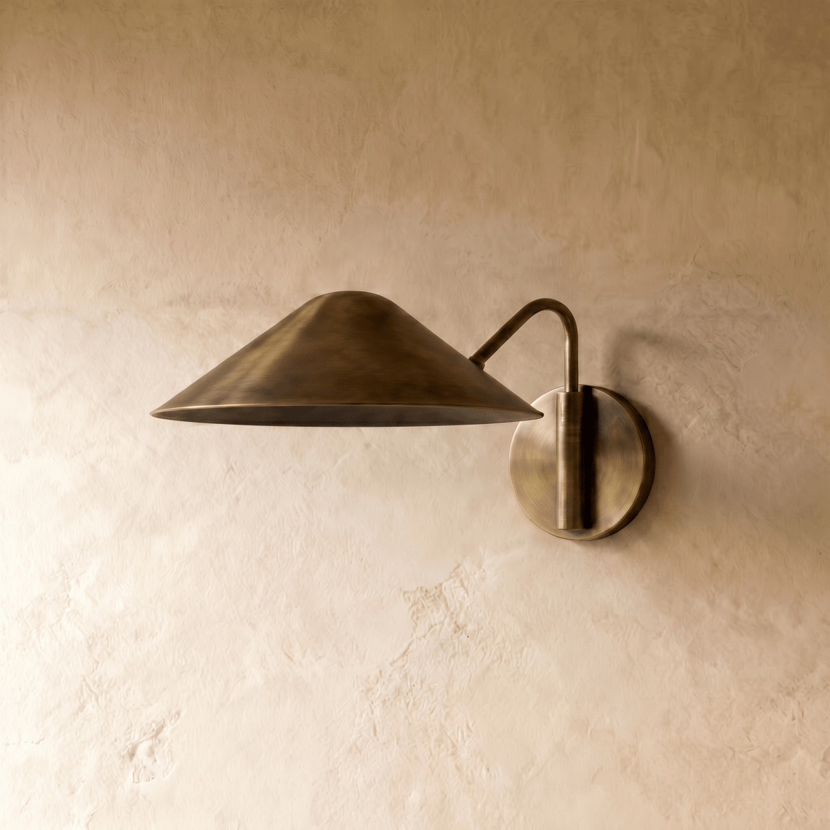 Clérachic cone-shade wall sconce in vintage brass, shown from a slightly closer studio angle on a plaster wall.