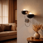 Clérachic wall lamp in chrome lighting a living room corner beside a sofa and a speckled vase.