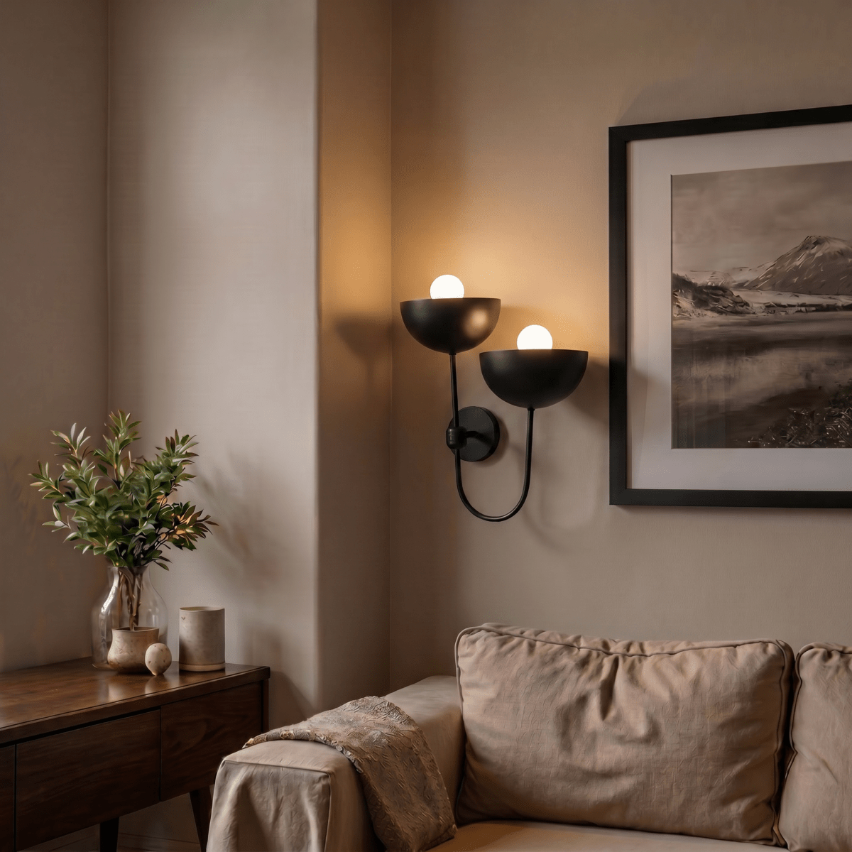 Clérachic wall lamp in matte black beside a framed mountain photograph above a living room sofa.
