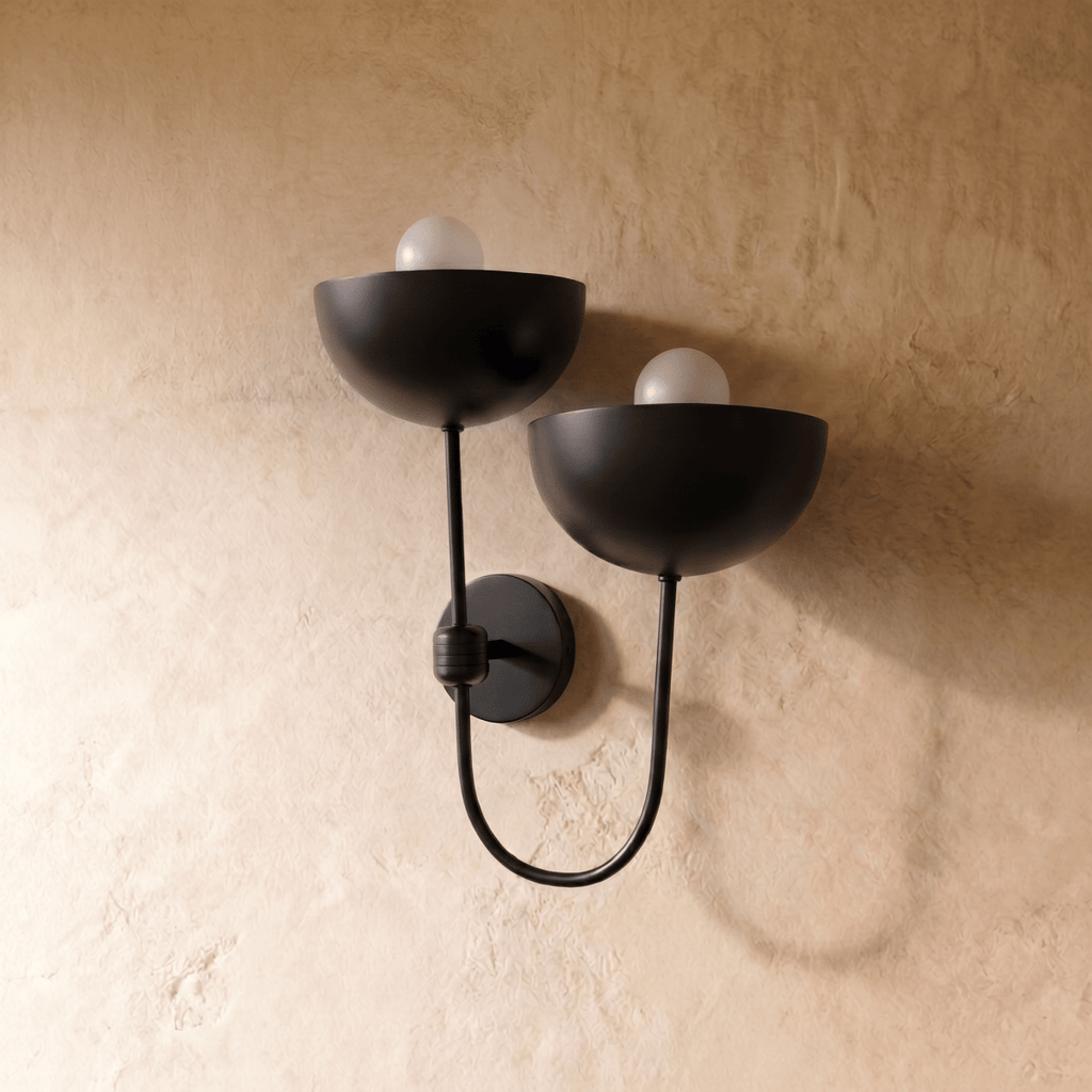 Clérachic wall lamp in matte black shown from another angle, two globe bulbs glowing beneath the domes.