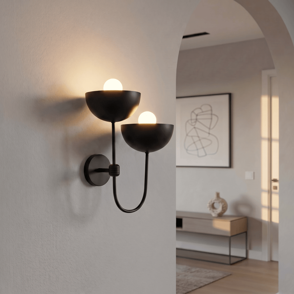 Clérachic wall lamp in matte black mounted by an archway leading into a bright entry hall.