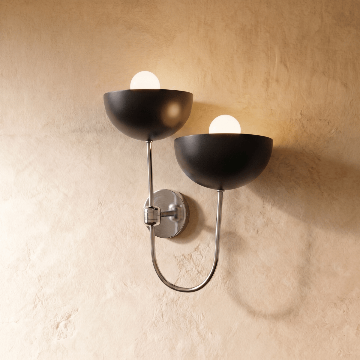 This Clérachic wall lamp in chrome, twin black dome shades curving from a looping silver arm.