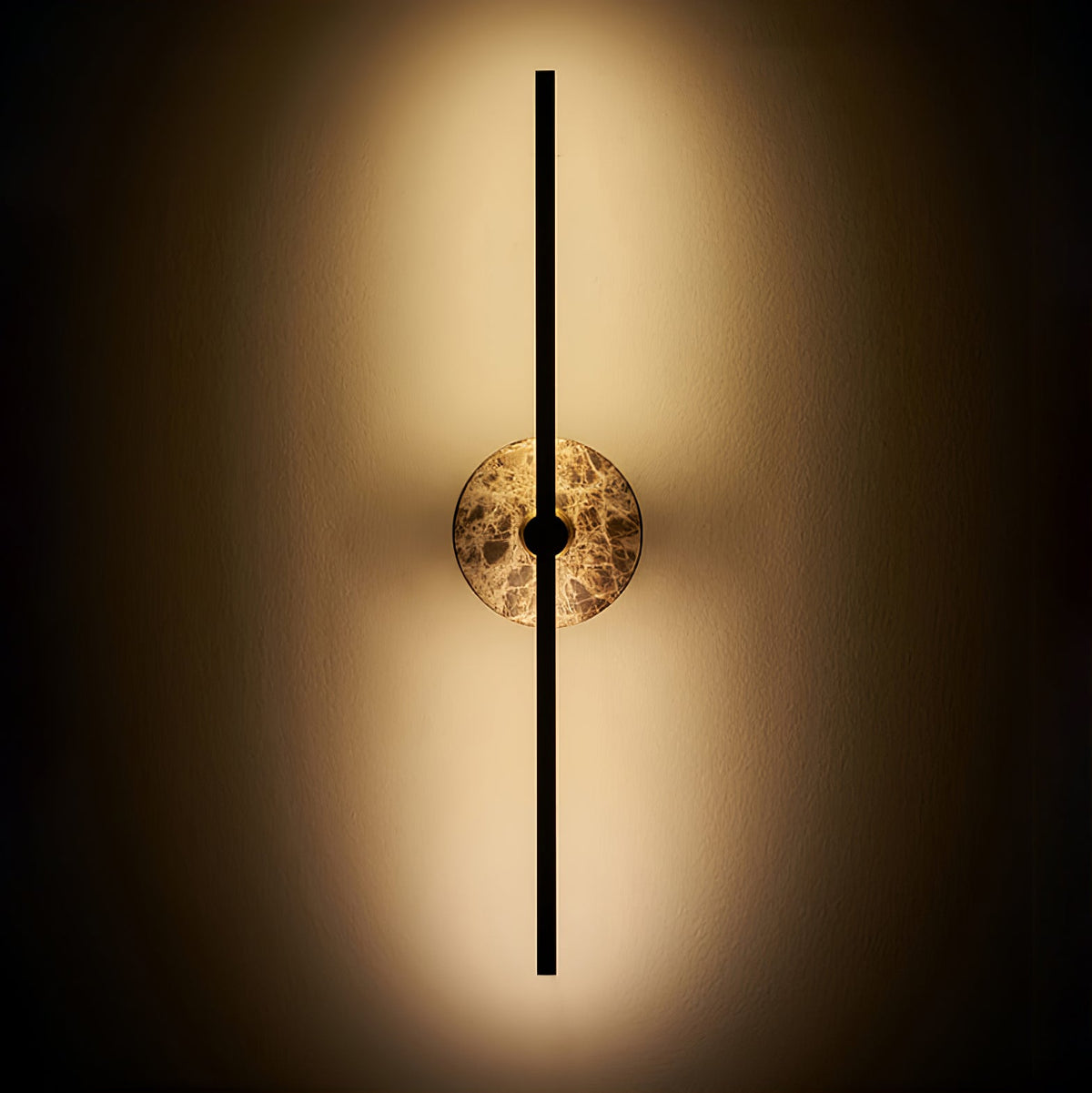 Clérachic wall light illuminated on a dark background, warm light spilling around its brown marbled stone disc.
