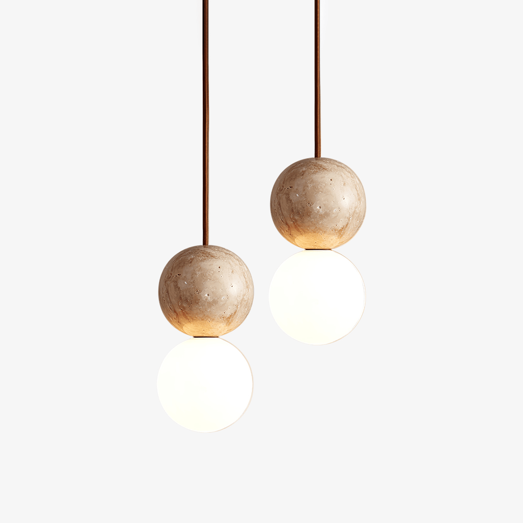 Close view of a Clérachic pendant pairing a travertine sphere with an opal glass globe against a plain white backdrop.
