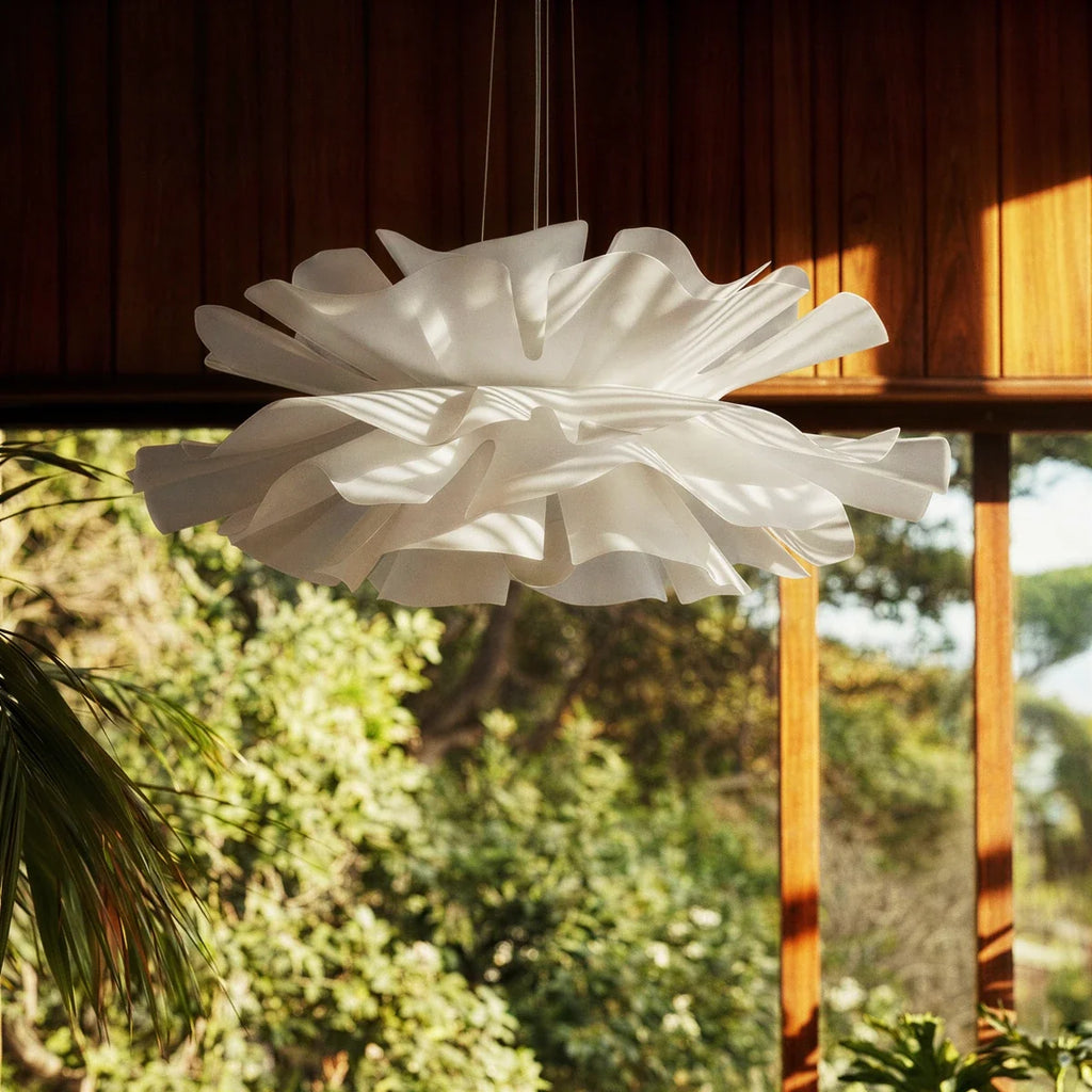 Clérachic flower chandelier unlit in daylight, window shadows falling across its white petals in front of a timber-framed garden window.