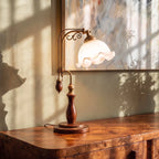 Clérachic table lamp in milky glass, a closer view glowing on a burl wood credenza in warm light.