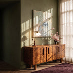 Clérachic table lamp with a milky glass shade glowing on a burl wood credenza beneath an abstract print.