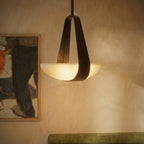 Clérachic pendant light seen close and lit beside a framed painting, the frosted glass dish spreading an even wash over a green upholstered bench.