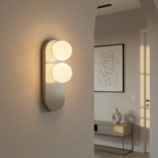 A Clérachic wall light glows through an archway, its two glass globes lighting a console table beyond.