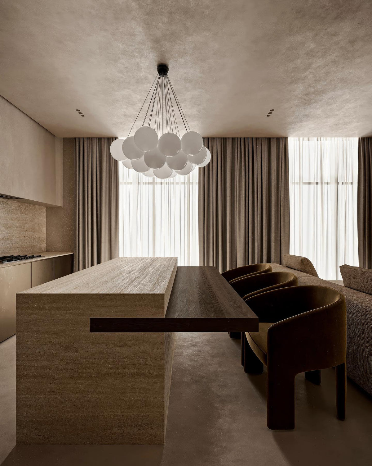 A chandelier with smoky-grey globes and a dark ceiling cap hangs in an open kitchen and dining space, a different fixture from this Clérachic chandelier's frosted white globes.