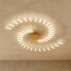 Clérachic starburst chandelier in gold, the same swept comma, packed with frosted tubes at the end of every rod.